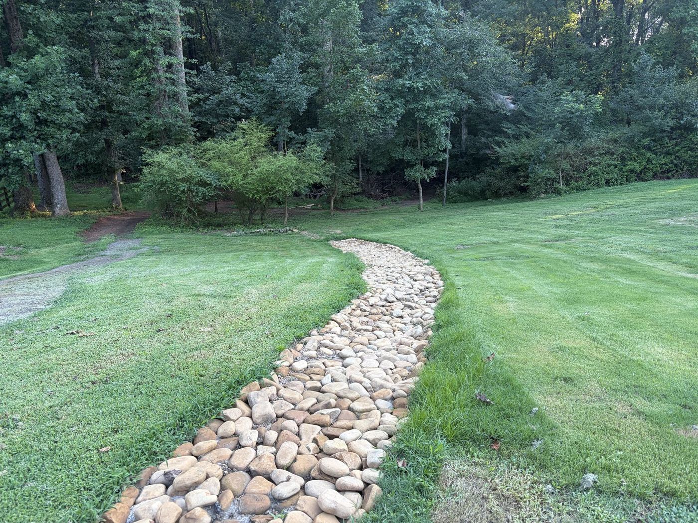River rock dry creek bed built through a lawn to carry runoff